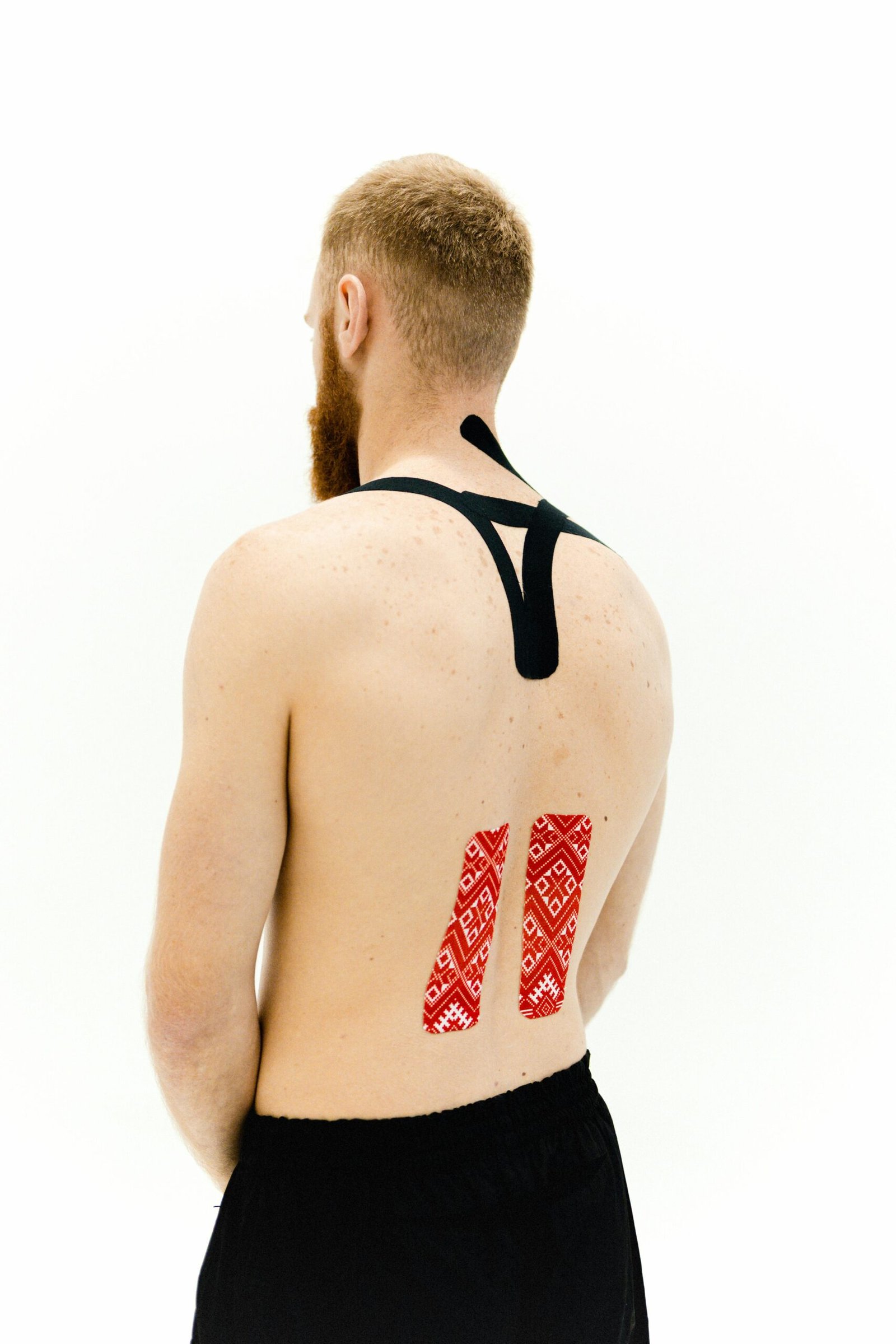 A man with kinesio tape applied to his back for muscle support. Enhances athletic performance and recovery.